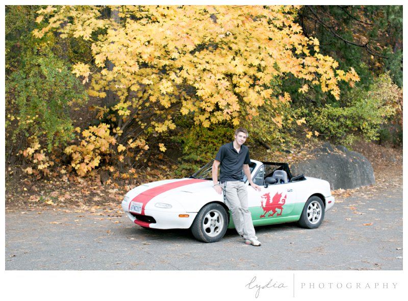 Senior guy by his his Miata Mazda with a fall tree behind for high school Ghidotti senior portraits at Little Deer Creek Trail in Nevada City, California