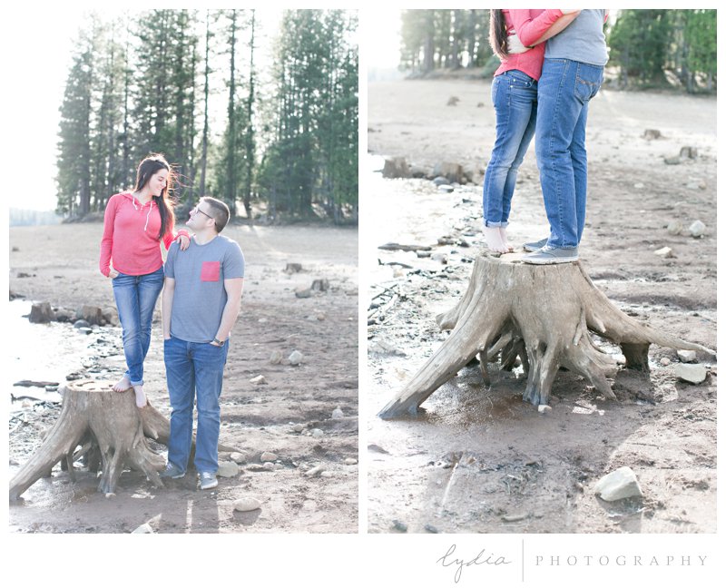 Bride and groom by a lake on a stump at a Tahoe Forest engagement session at the Tahoe National Forest and at Scotts Flat Lake in Nevada City, California.