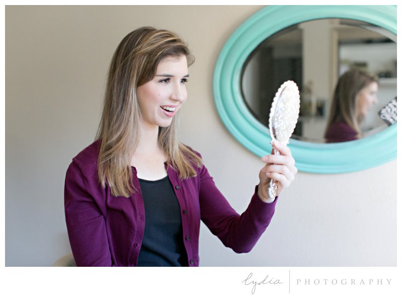 Girl looking into a mirror after professional makeup by Polish & Pout for BJU senior portraits in Roseville, California.