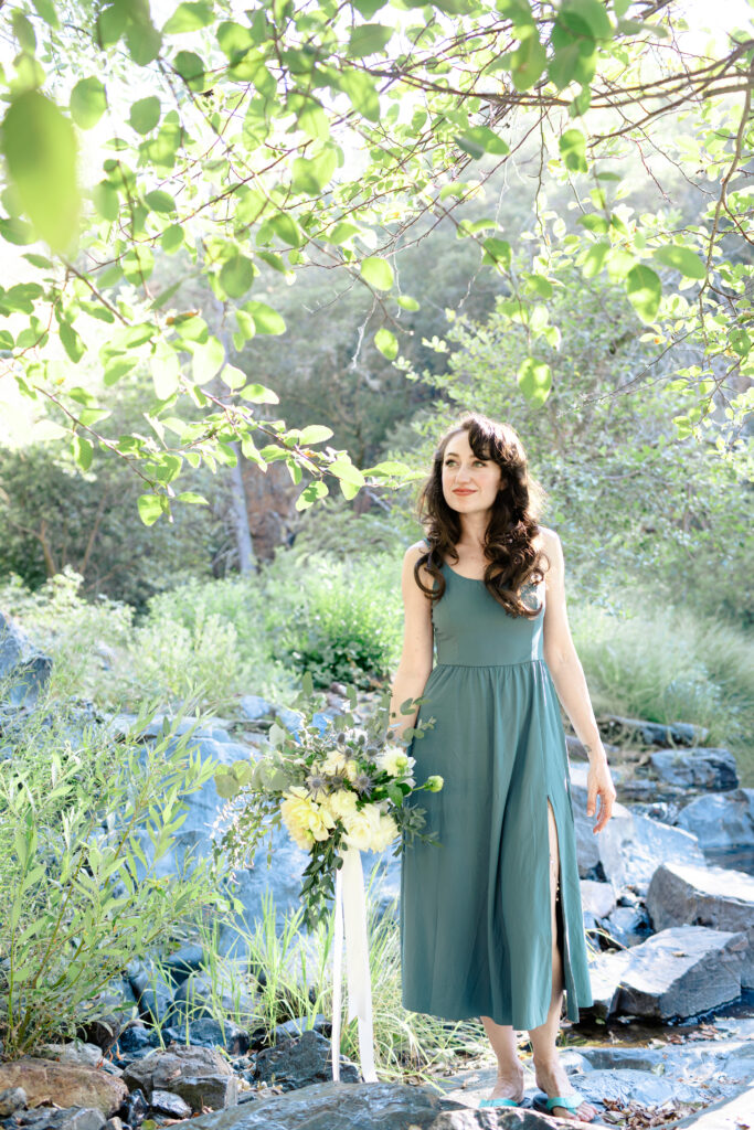 Bride holding bouquet next to stream at Lake Wildwood wedding in Penn Valley, California