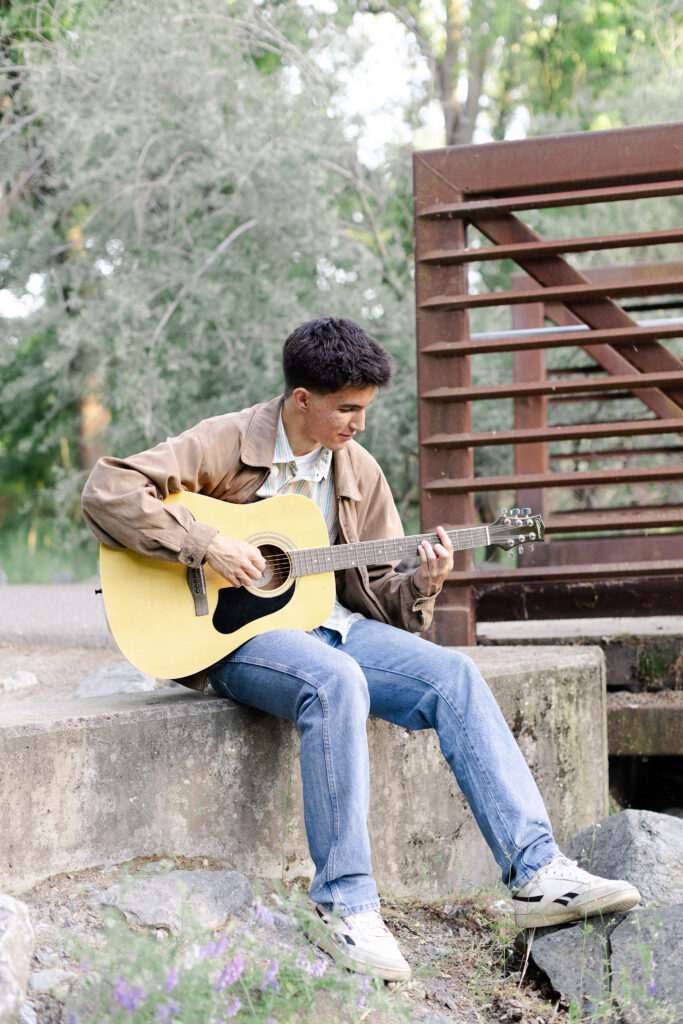 Young man playing guitar at Roseville senior portrait session.