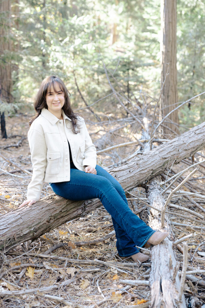 Teen girl sitting on log at Nevada City senior portrait session.