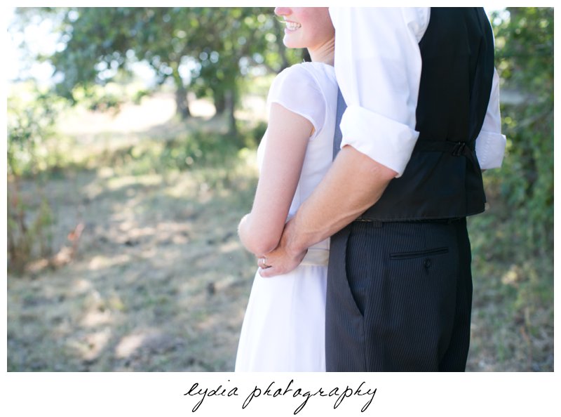 Grooms hands around brides waist at vintage travel barn wedding in Sebastopol, California