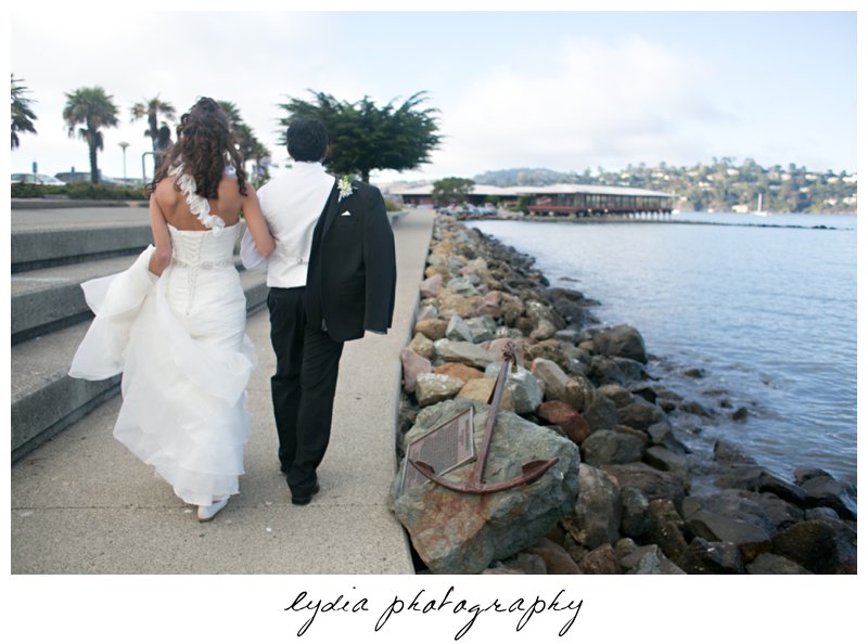 Bride and groom walking alone the shoreline at elegant Sausalito, California wedding at The Spinnaker