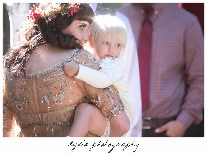 Bride wearing Anthropologie gold dress with baby at intimate rustic vintage woodland wedding in Tahoe, California