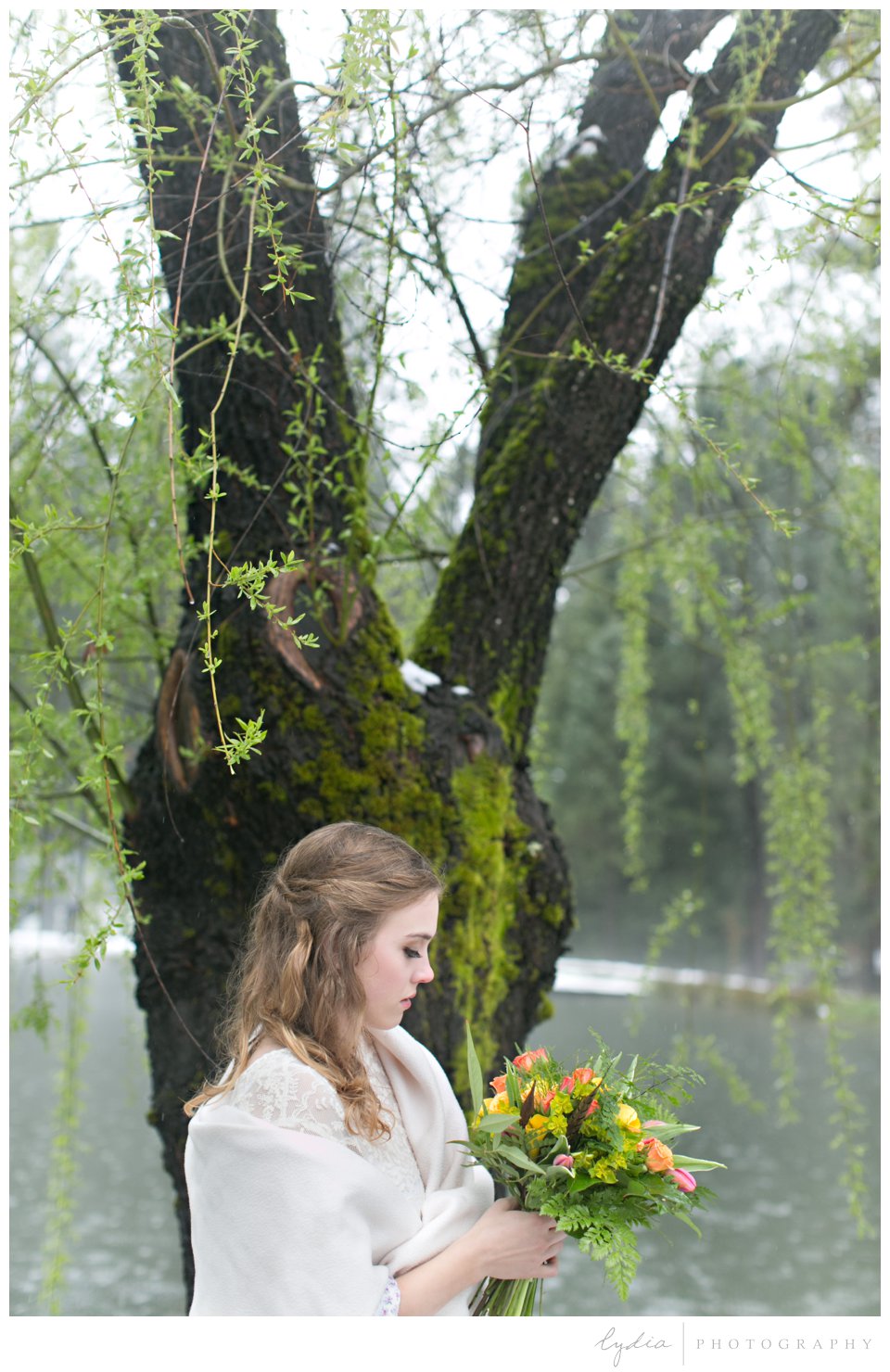 bride in front of pond behind holding a wedding bouquet