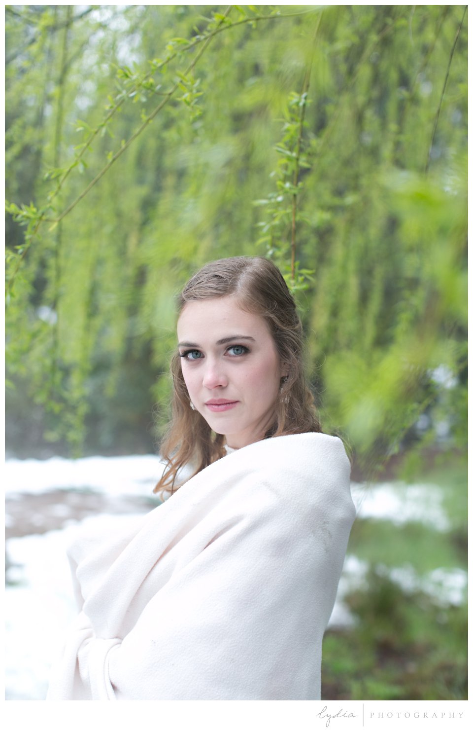bride in the snow with trees and pond behind in Grass Valley, California