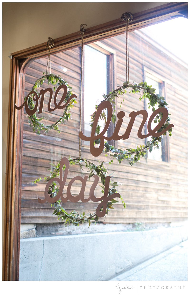 Round garland wedding signs hanging in a window