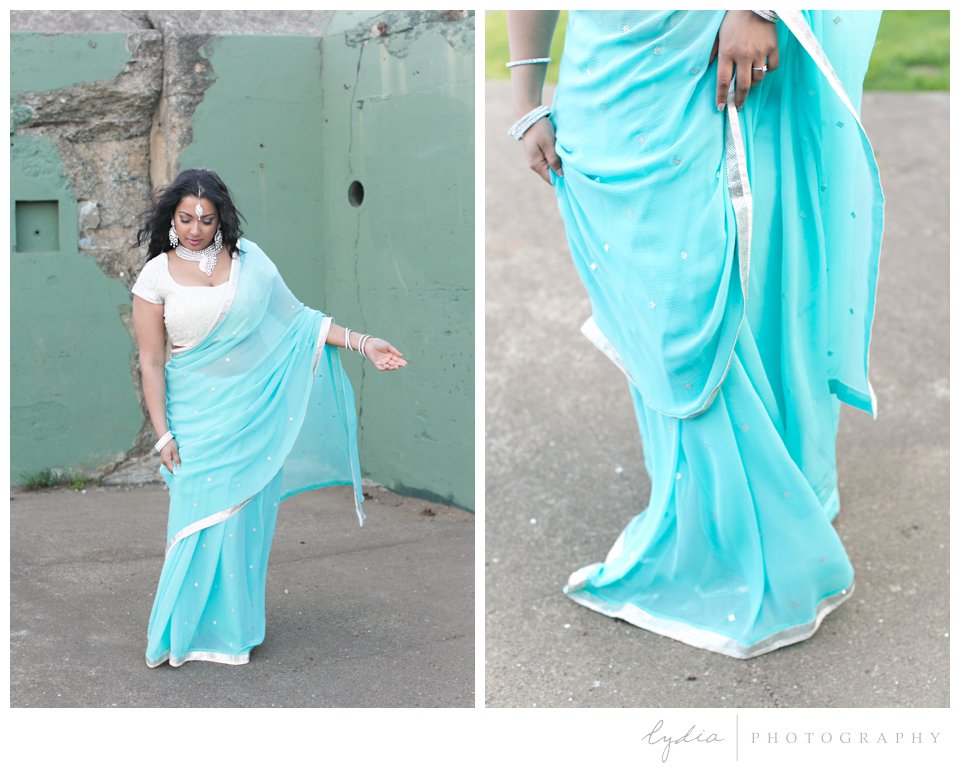 Indian bride wearing turquoise sari and silver bindi in the blowing wind at an old Army fort