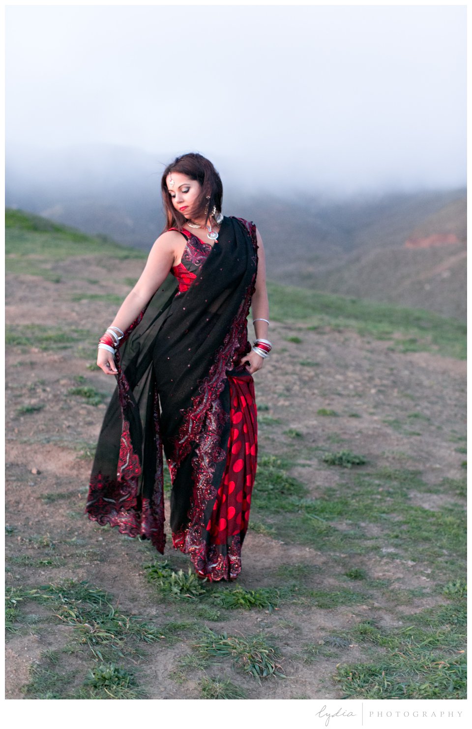 Indian bride wearing red sari and gold bindi on a cliff at sunset at Rodeo Beach