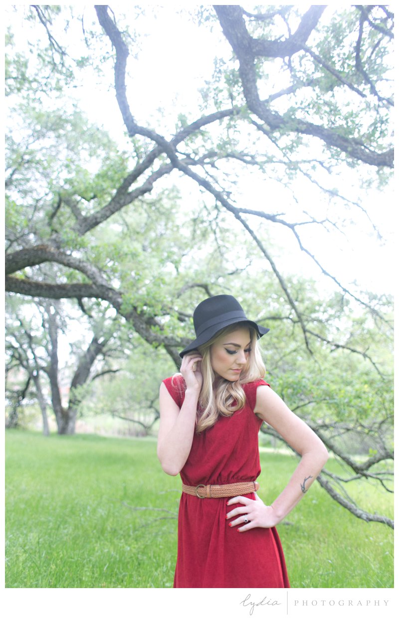 Anthropologie styled senior wearing a red vintage dress and black felt hat in a wildflower field in Roseville, California.
