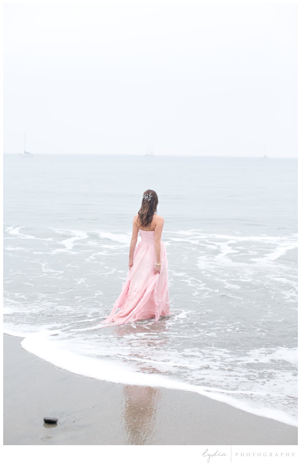 Bride in pink wedding dress in the ocean at a trash the dress shoot in Santa Barbara, California
