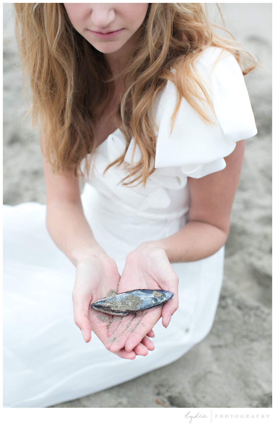 Bride holding a seashell on ocean beach in Santa Barbara, California