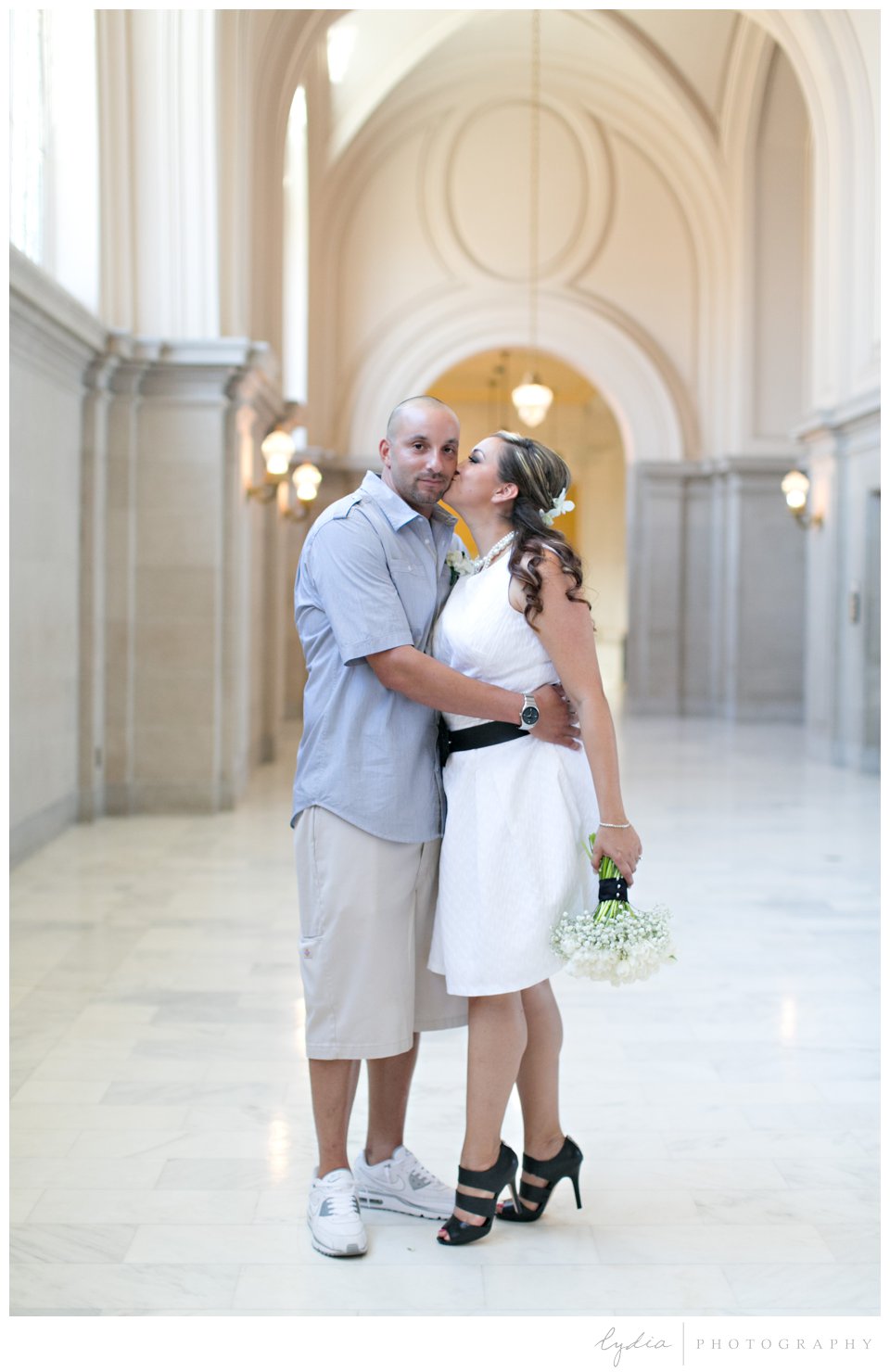 Bride kissing her groom in the hall at black and white City Hall wedding in San Francisco, California