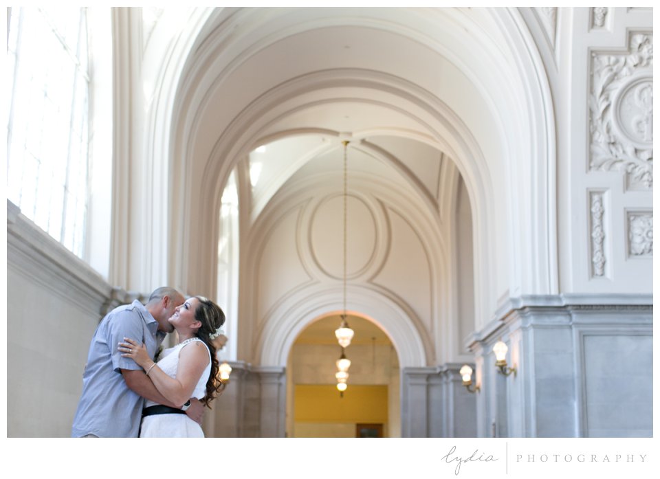 Groom kissing his bride at black and white City Hall wedding in San Francisco, California