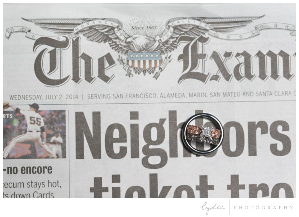 Bride's and groom's rings on a newspaper at black and white City Hall wedding in San Francisco, California