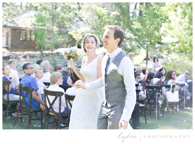Bride and groom walk down the aisle for a garden wedding at Roth Estate, in Grass Valley, California 