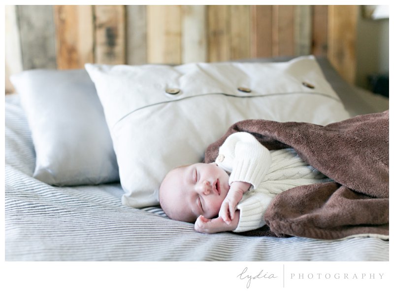 Baby wrapped in a blanket on the bed for a Sacramento lifestyle newborn photography in Roseville, California