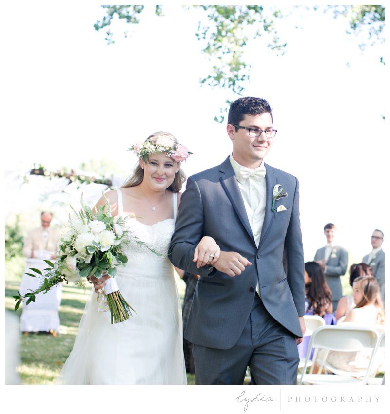 Bride carrying bouquet and groom walking at a southern garden wedding in Cottonwood, California.