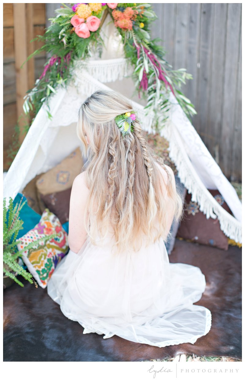 Bride by a flower decorated tepee at southwest boho wedding inspiration in Grass Valley, California.