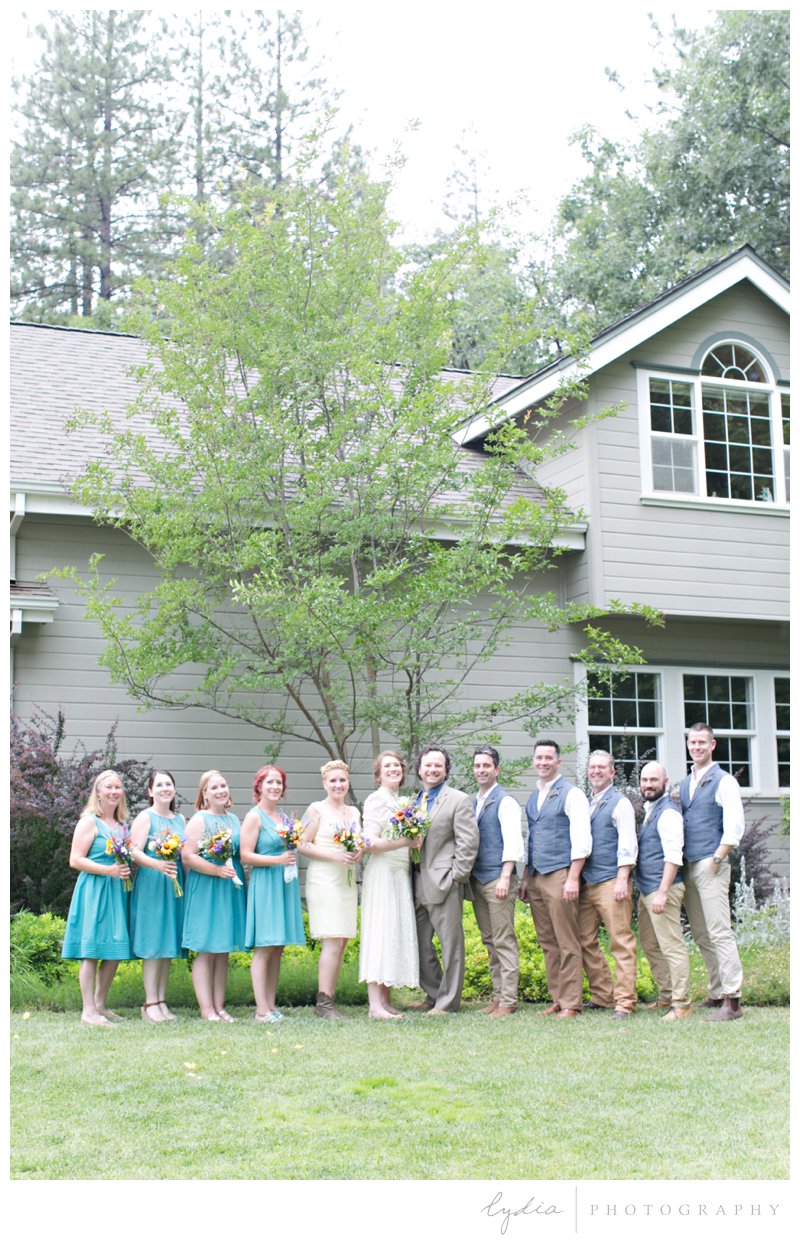 Wedding bridal party in yellow and blue dresses and matching vests at rustic garden wedding in Chicago Park, California.