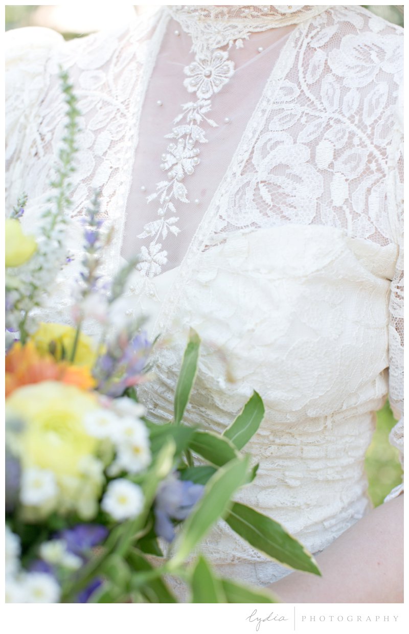 Bride wearing a vintage, lace dress and holding a wildflower bouquet at Grass Valley garden wedding in Chicago Park, California.