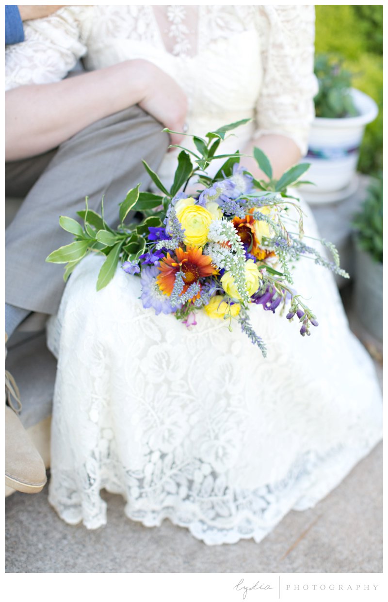 Bride and groom sitting on the porch with a bouquet at rustic garden wedding in Chicago Park, California.