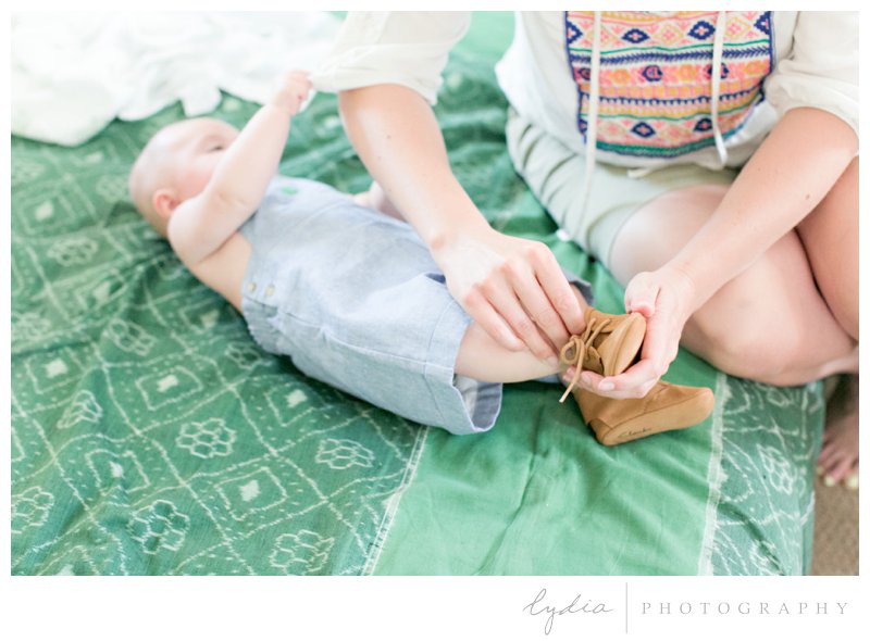 A preppy baby getting his little leather shoes on at rustic garden wedding in Chicago Park, California.