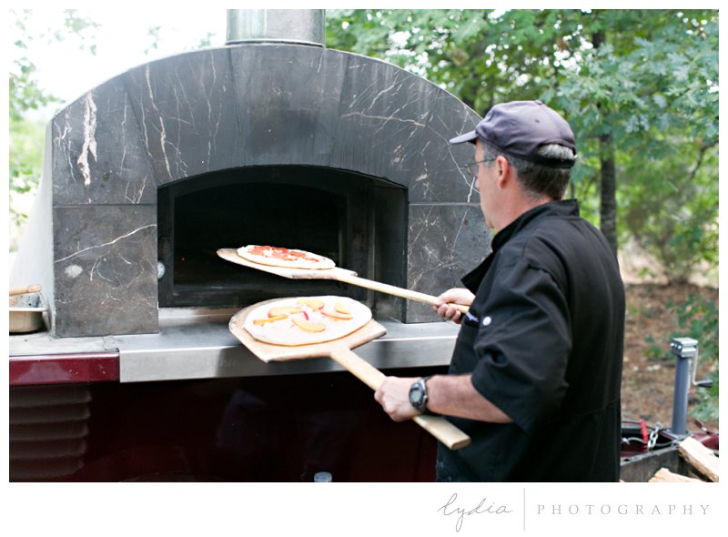 Woodfired pizza going in the oven at Grass Valley garden wedding in Chicago Park, California.