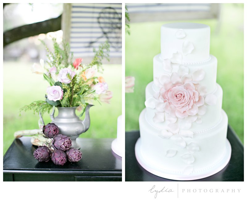 Purple artichokes, silver teapot floral arrangement, and pink sugar rose cake at French Countryside wedding at North Star House in Grass Valley, California.