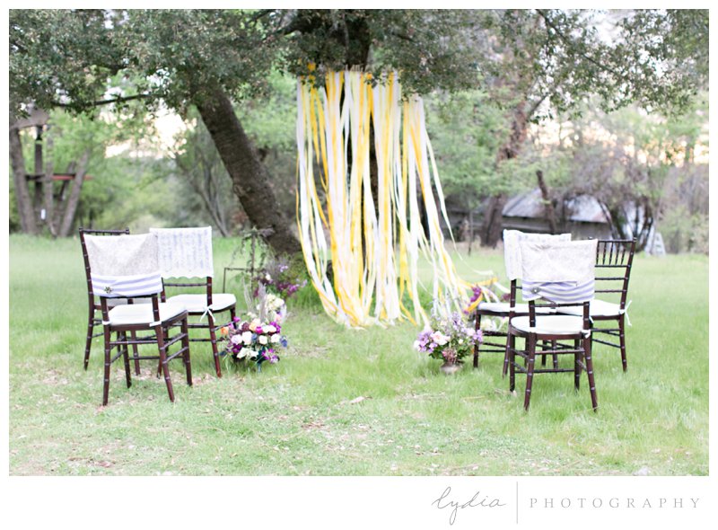 Chiavari chairs, ribbon backdrop at alter, and floral arrangements along the aisle at French Countryside wedding at North Star House in Grass Valley, California.