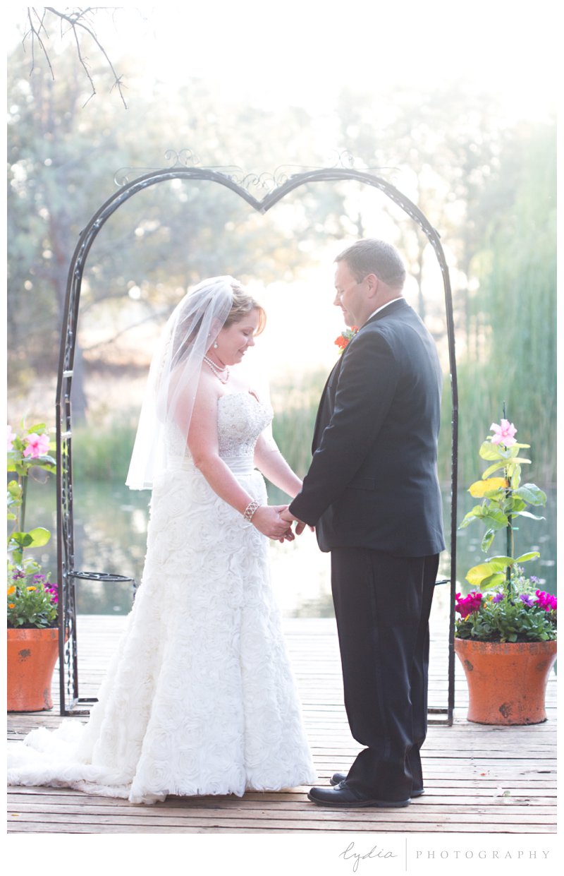 Bride and groom under an arch for a lakeside wedding in Browns Valley, California.