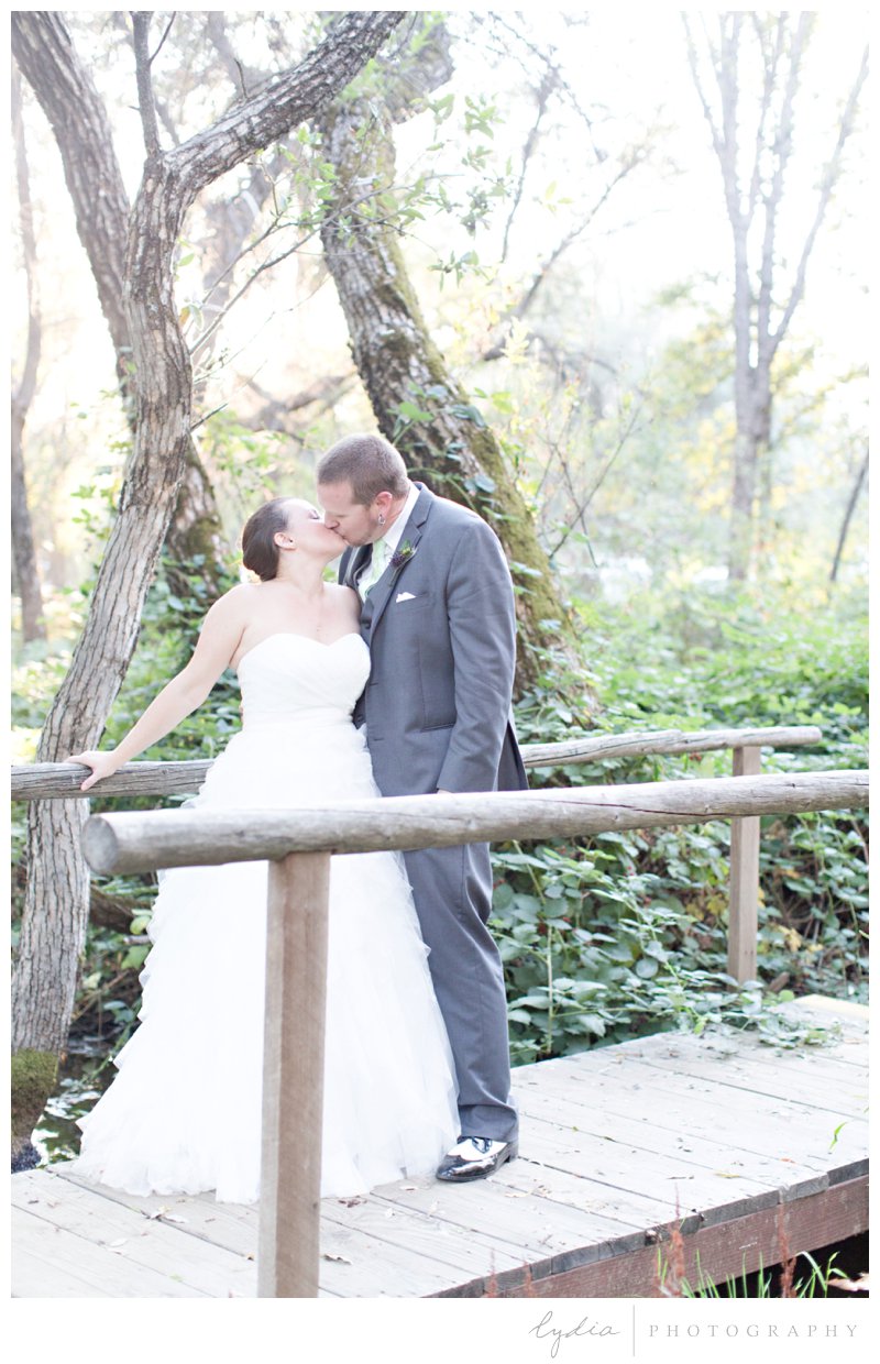 Bride and groom on a bridge kissing at Squirrel Creek Ranch wedding in Grass Valley, California.
