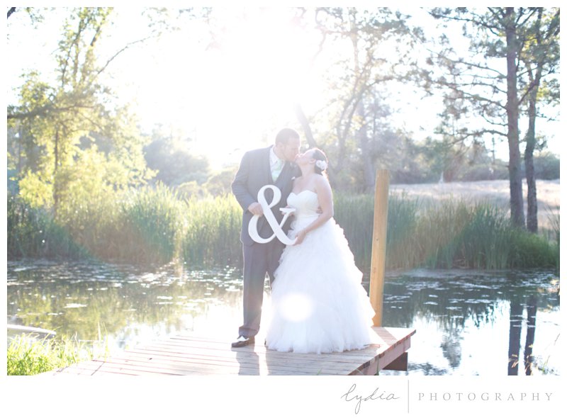 Bride and groom holding a & sign at a barn at Squirrel Creek Ranch wedding in Grass Valley, California.