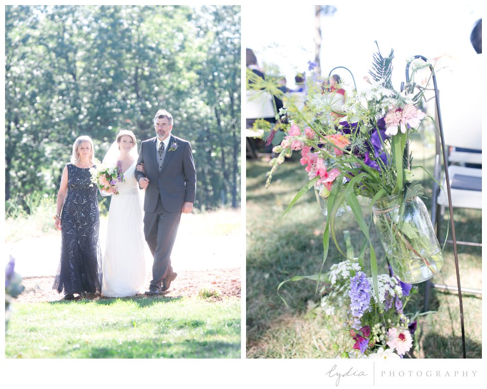 Bridal processional and jars of wildflowers lining the aisle at Lucchesi Vineyards in Grass Valley, California.