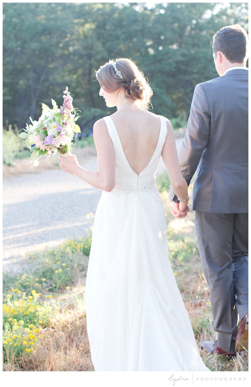 Bride holding bouquet and walking with groom at Lucchesi Vineyards wedding in Grass Valley, California.