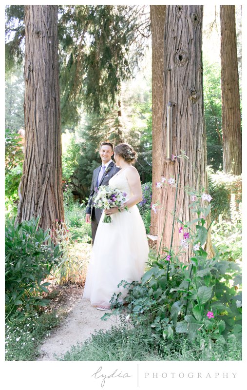 Bride and groom walking through the garden in the Tahoe forest at Harmony Ridge Lodge in Nevada City, California.