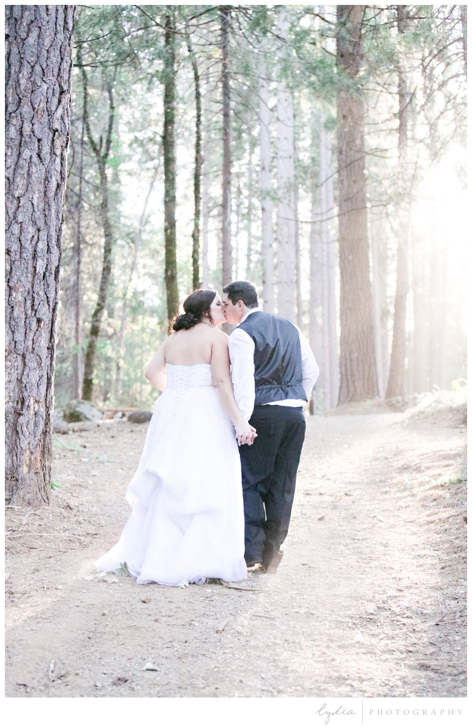 Bride and groom walking in forest at Northern Queen Inn Wedding in Nevada City, California.
