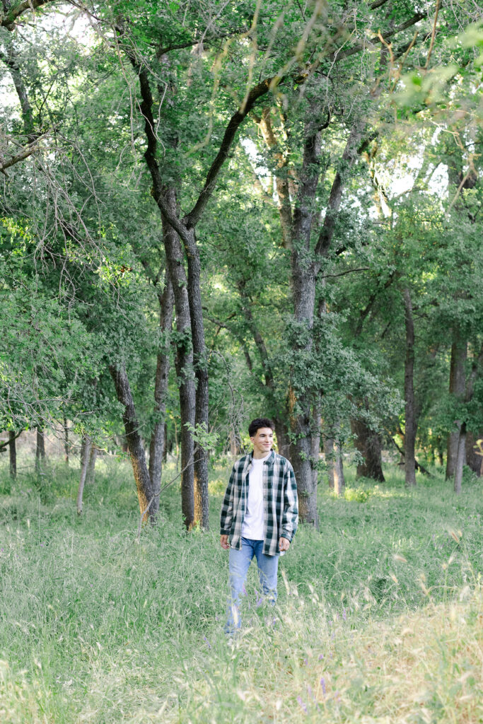 Young man walking through the trees at a Roseville senior portrait session.