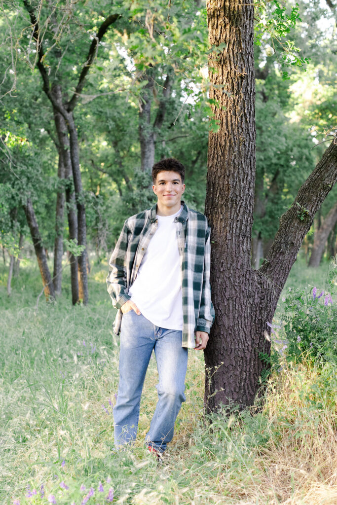 Young man leaning against a tree at a Roseville senior portrait session.